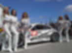 Skin City models standing next to a WeatherTech racecar.