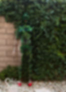 A body painted model camouflaged against a wall of ivy and wearing red high heels