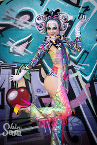 A body painted model standing in front of a graffiti wall