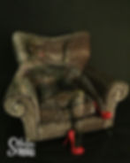A body painted model camouflaged in a leopard print lounge chair and wearing red high heels